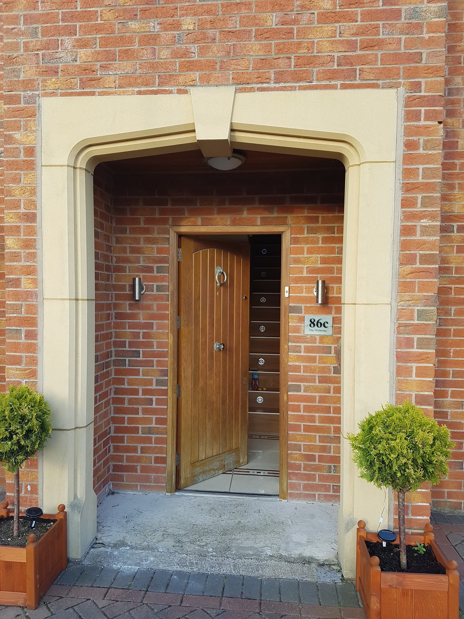 Brick porch with stone arch surround and arched timber front door