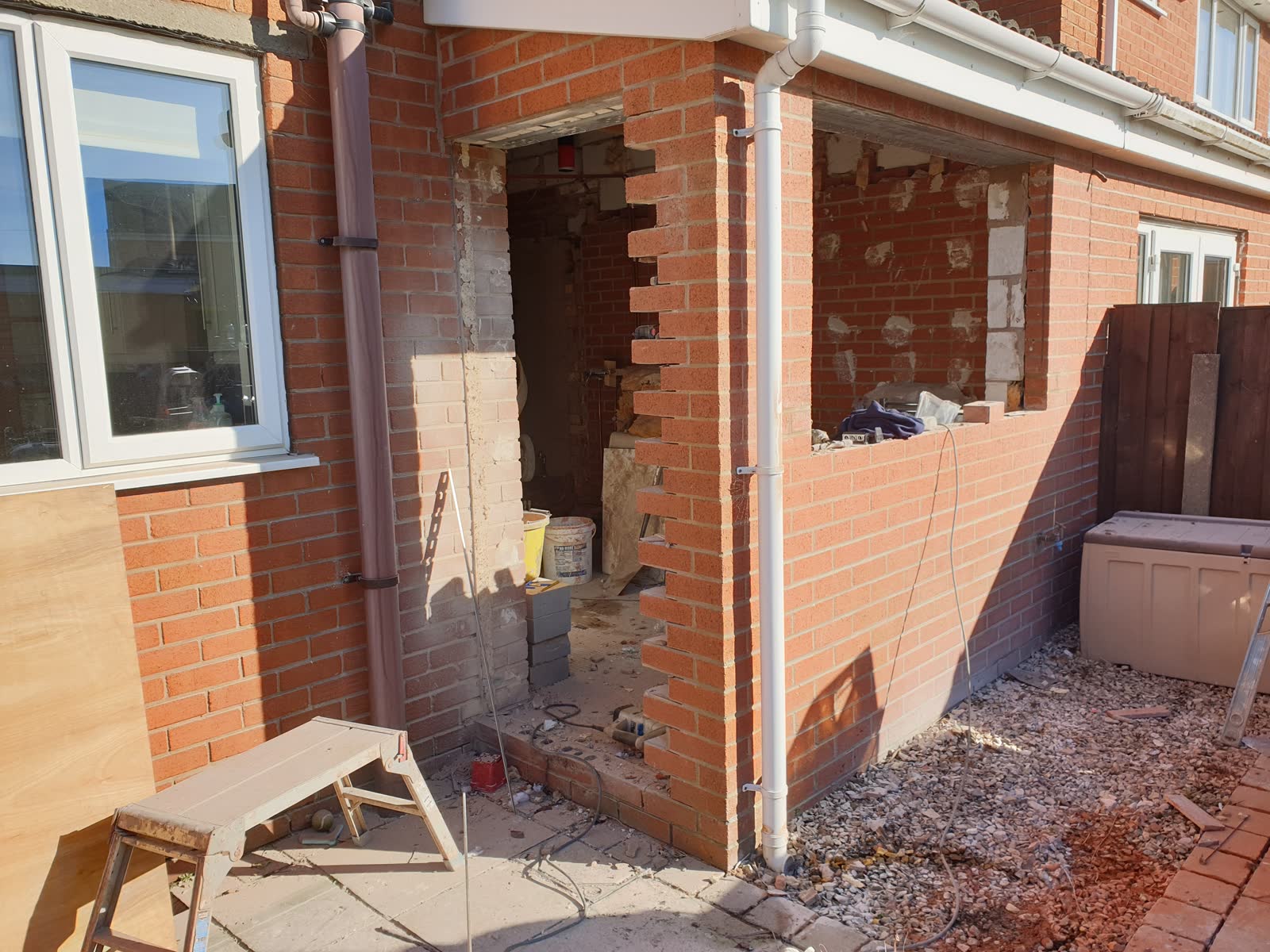 Red brick house extension under construction with window and door openings
